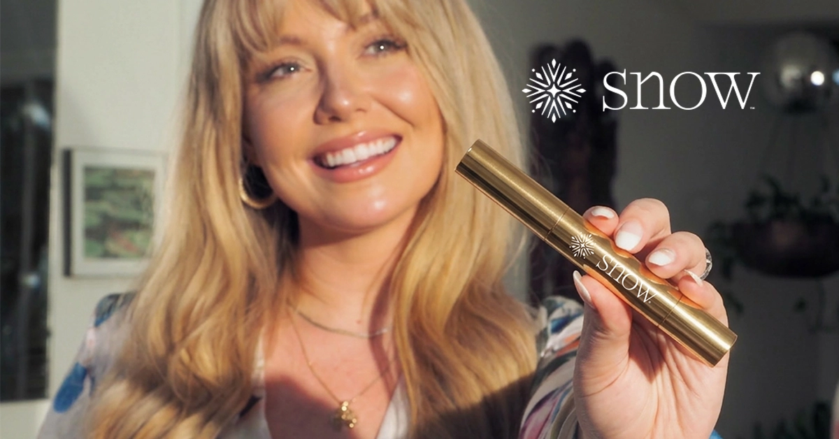A smiling woman holding a Snow whitening pen